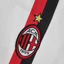 Emblema do AC Milan na camiseta branca retro 11/12, destacando detalhes icônicos do clube.