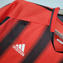 Detalhe da camiseta AC Milan Away 04/05 Retro Olympic com design em vermelho e preto, destacando logo da adidas.