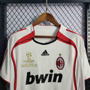 Camisa do AC Milan Away 06/07 com detalhes da Liga dos Campeões, em exibição em cabide.