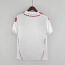 Camisa retrô branca do AC Milan Away 11/12, vista traseira, destacando detalhes em verde e vermelho.