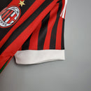 Camisa retrô AC Milan Away 11/12 na cor vermelha e preta com detalhes em branco e logo do clube.