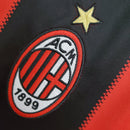 Logo do AC Milan em uniforme de futebol, destaque para o emblema e a estrela acima, representando a história do clube.