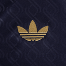 Logotipo dourado da Adidas em fundo azul, destacando o design icônico da marca.