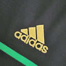 Logo da Adidas em camiseta preta com detalhes em verde, representando qualidade e estilo para torcedores.