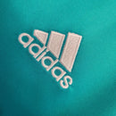 Logo da Adidas em um fundo azul claro, destacado em bordado branco.