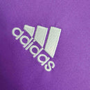 Logo da Adidas em relevo, em tecido roxo, destacando as três listras características da marca.