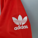 Logo da Adidas em um tecido vermelho, parte da camisa retro do Manchester United.
