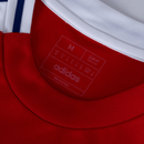 Detalhe da etiqueta da camiseta Arsenal home 24/25, com logo da Adidas e informações sobre o tamanho.
