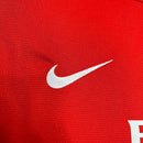 Logotipo da Nike em uma camisola de futebol vermelha, representando a marca Arsenal Home.