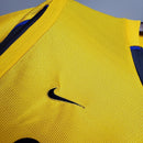 Detalhe da camisa Arsenal Home 99/00 Retro da Nike, mostrando a cor amarela vibrante e o logo na lateral.