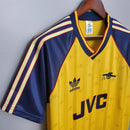 Camisa retro do Arsenal de 1988/1989 na loja olímpica, com detalhes em amarelo e azul. Design clássico da Adidas.