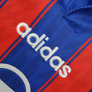 Detalhe da camisa do Bayern München 1995 com logo da Adidas em destaque e cores vibrantes.