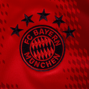 Emblema do FC Bayern München em camiseta vermelha, destacando as cinco estrelas.