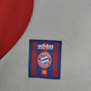Detalhe do patch do Bayern München na camisa retro Adidas 98/99, destaque para a autenticidade e design clássico.