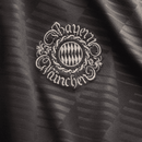 Detalhe do emblema Bayern München em tecido escuro, ideal para a coleção Oktoberfest 24/25.