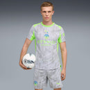 Jogador segurando bola em camisa Manchester City 2025/26 III com detalhes em neon, mostrando estilo e esporte.