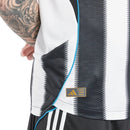 Camisola Principal Newcastle United 2025/26 Adidas com listas verticais pretas e brancas, detalhes em azul e inscrição “Howay the Lads” na nuca.