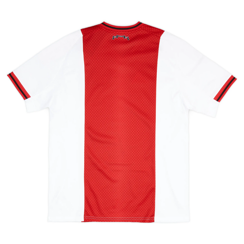 Camisola principal do Ajax 2025/26 Adidas em branco e vermelho com faixa central em padrão gradiente, gola em V e detalhes icónicos da cidade de Amesterdão.