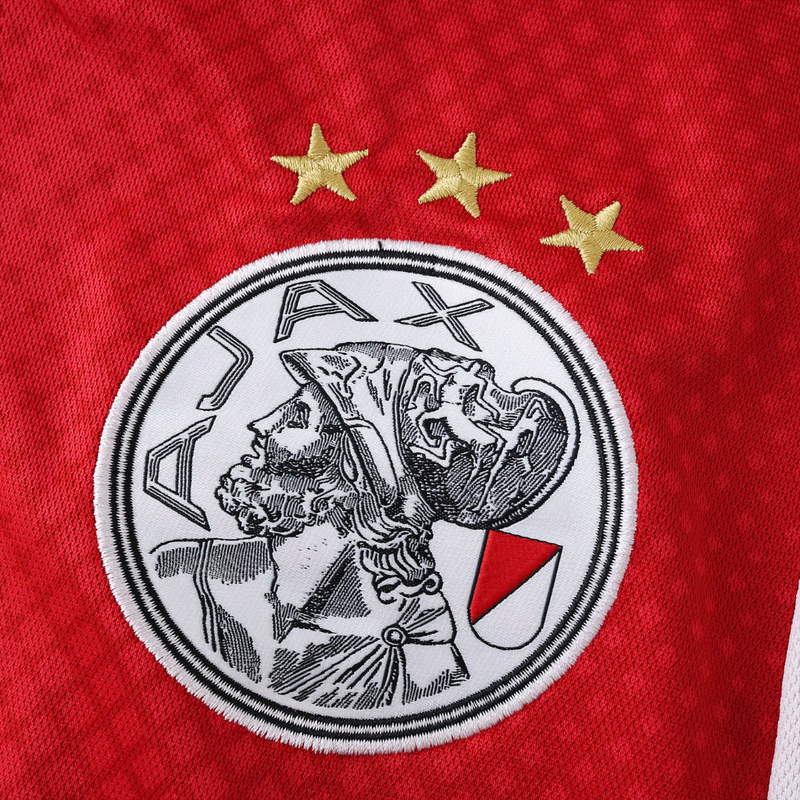 Camisola principal do Ajax 2025/26 Adidas em branco e vermelho com faixa central em padrão gradiente, gola em V e detalhes icónicos da cidade de Amesterdão.