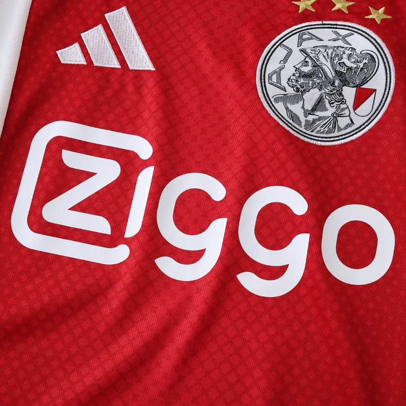 Camisola principal do Ajax 2025/26 Adidas em branco e vermelho com faixa central em padrão gradiente, gola em V e detalhes icónicos da cidade de Amesterdão.