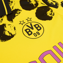 Camisola Borussia Dortmund Home 2025 KidSuper x CWC detalhes do logo BVB 09 em amarelo e preto.
