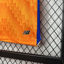 Conjunto infantil FC Porto laranja alternativo 2024/25 com detalhe da marca New Balance.