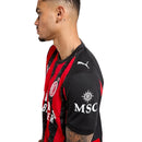 Camisola principal do AC Milan 2025/26 com riscas vermelhas e pretas estilizadas em forma de chamas, gola preta e escudo em vermelho e branco