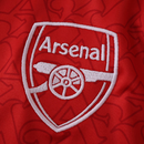 Camisola principal do Arsenal 2025/26 da Adidas, em vermelho com mangas brancas e padrão gótico subtil com a letra “A”, gola redonda e logos em branco.