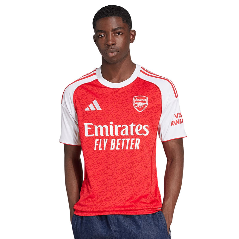 Camisola principal do Arsenal 2025/26 da Adidas, em vermelho com mangas brancas e padrão gótico subtil com a letra “A”, gola redonda e logos em branco.