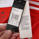 Camisola oficial do Bayern de Munique 2025–2026 em vermelho com detalhes brancos, escudo do clube e lema “Mia San Mia” bordado na parte de trás da gola.