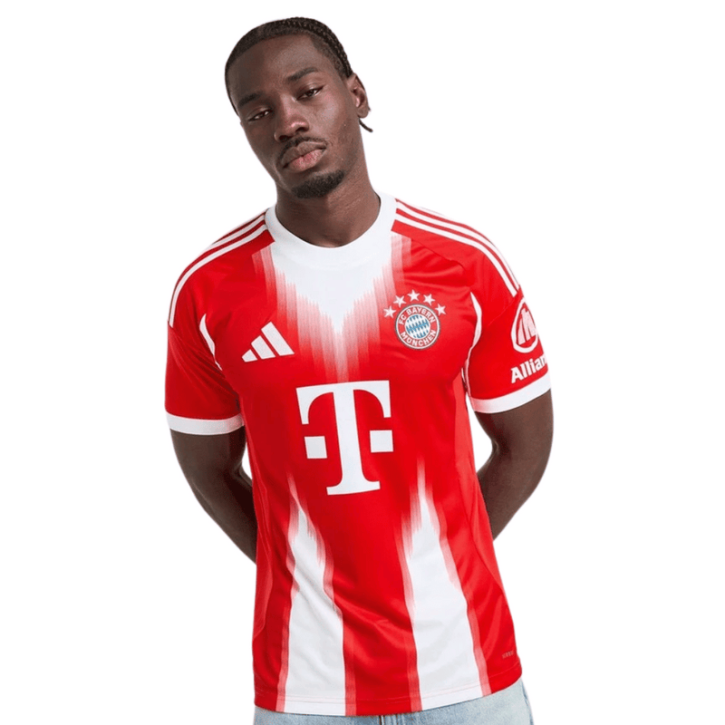 Camisola oficial do Bayern de Munique 2025–2026 em vermelho com detalhes brancos, escudo do clube e lema “Mia San Mia” bordado na parte de trás da gola.