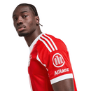 Camisola oficial do Bayern de Munique 2025–2026 em vermelho com detalhes brancos, escudo do clube e lema “Mia San Mia” bordado na parte de trás da gola.