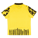 Camisola principal amarela e preta do Borussia Dortmund 2025 com padrão hexagonal nos ombros e detalhes artísticos pintados à mão, colaboração Puma x KidSuper.