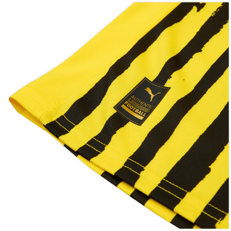 Camisola principal amarela e preta do Borussia Dortmund 2025 com padrão hexagonal nos ombros e detalhes artísticos pintados à mão, colaboração Puma x KidSuper.