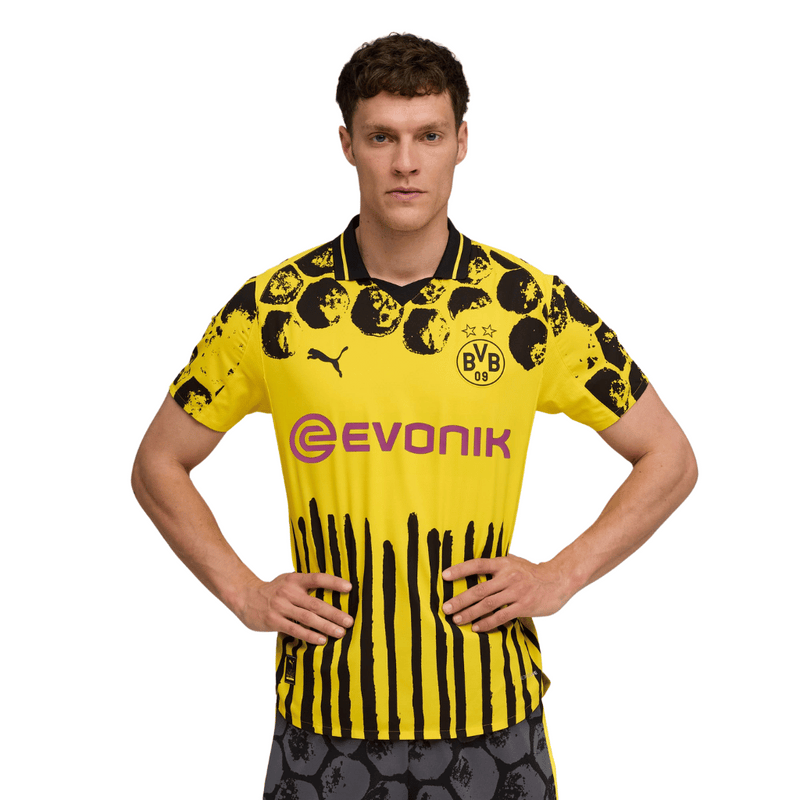 Camisola principal amarela e preta do Borussia Dortmund 2025 com padrão hexagonal nos ombros e detalhes artísticos pintados à mão, colaboração Puma x KidSuper.