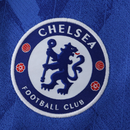 Camisola principal do Chelsea 2025/26 da Nike em azul royal com estampado gráfico inspirado em Londres, gola em V branca e detalhes em vermelho e branco.