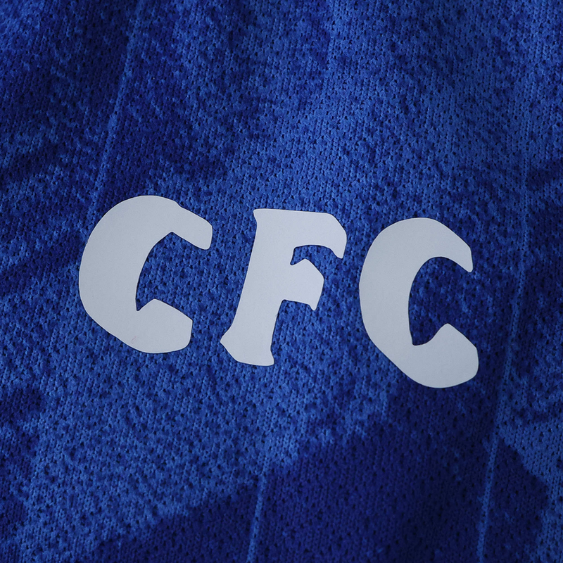 Camisola principal do Chelsea 2025/26 da Nike em azul royal com estampado gráfico inspirado em Londres, gola em V branca e detalhes em vermelho e branco.