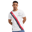 Camisola branca do Manchester City 25/26 com faixa diagonal preta e vermelha, padrão Poznań e detalhes artísticos da colaboração KidSuper x Puma