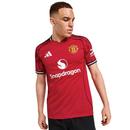 Camisola principal do Manchester United 2025/26 Adidas vermelha com detalhes pretos e brancos, padrão abstrato nos ombros e inscrição “Theatre of Dreams” nas costas.