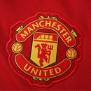 Camisola principal do Manchester United 2025/26 Adidas vermelha com detalhes pretos e brancos, padrão abstrato nos ombros e inscrição “Theatre of Dreams” nas costas.
