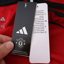Camisola principal do Manchester United 2025/26 Adidas vermelha com detalhes pretos e brancos, padrão abstrato nos ombros e inscrição “Theatre of Dreams” nas costas.