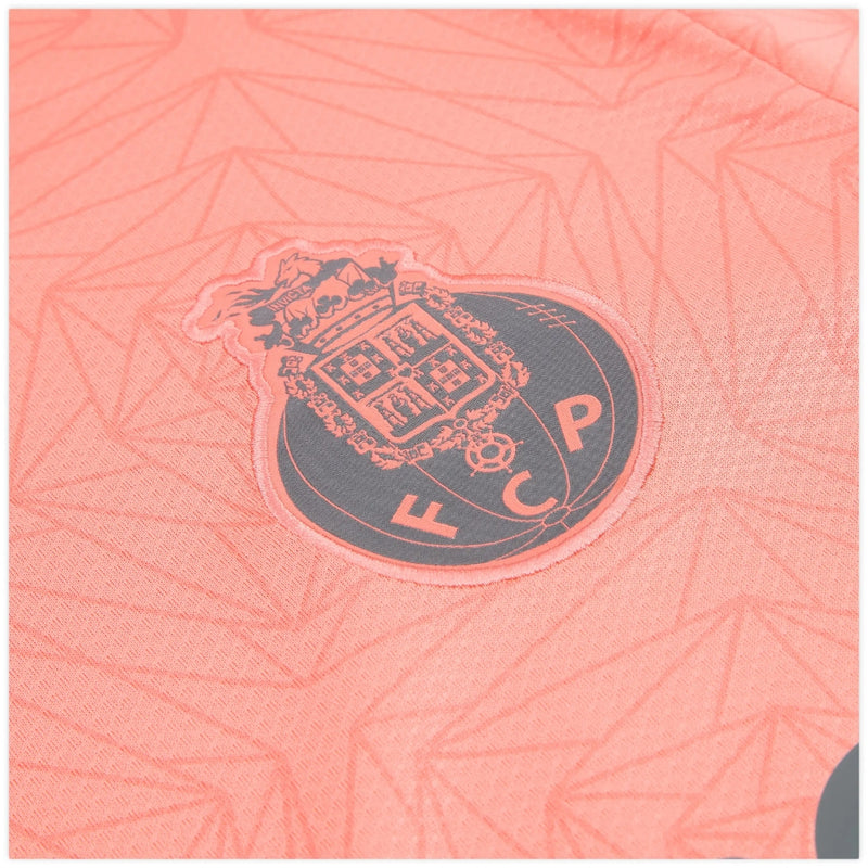 Camisola secundária FC Porto 2025/26 da New Balance, salmão com padrão floral e detalhes em cinzento, escudo e logótipos em tons harmoniosos.