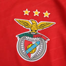 Camisola titular do Benfica 2024/25 com chevrons em relevo, gola em V branca, fundo vermelho encarnado e detalhes em branco no escudo, Adidas e patrocinadores.