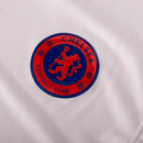 Emblema do Chelsea na camisa away 24/25, nas cores brancas e azuis, representando o Chelsea away.