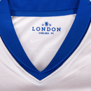 Detalhe do gola da camisa Chelsea away 24/25, branca e azul, com logo Nike e Chelsea FC.