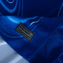 Chelsea home 24/25 Azul Olympic, detalhe do tecido com etiqueta ENGINEERED para autenticidade.