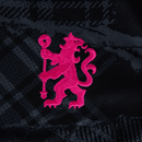 Emblema rosa do Chelsea third 24/25 em fundo preto, destacando o leão icônico do time.