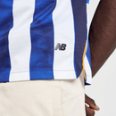 Camisa FC Porto 24/25 em azul e branco, detalhe da logomarca New Balance, vista lateral.