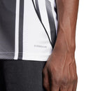 Camisola principal da Juventus 2025/26 da Adidas, com riscas pretas e brancas irregulares, gola TEAMGEIST, e detalhes em rosa no escudo e logos.