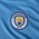 Logo da camisa de casa do Manchester City 24/25, em azul, com escudo do clube em destaque.